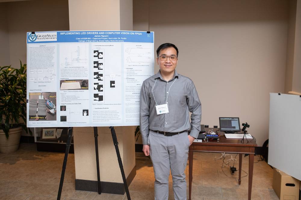 Electrical and Computer Engineering graduate student, James Nguyen, standing in front of his poster.